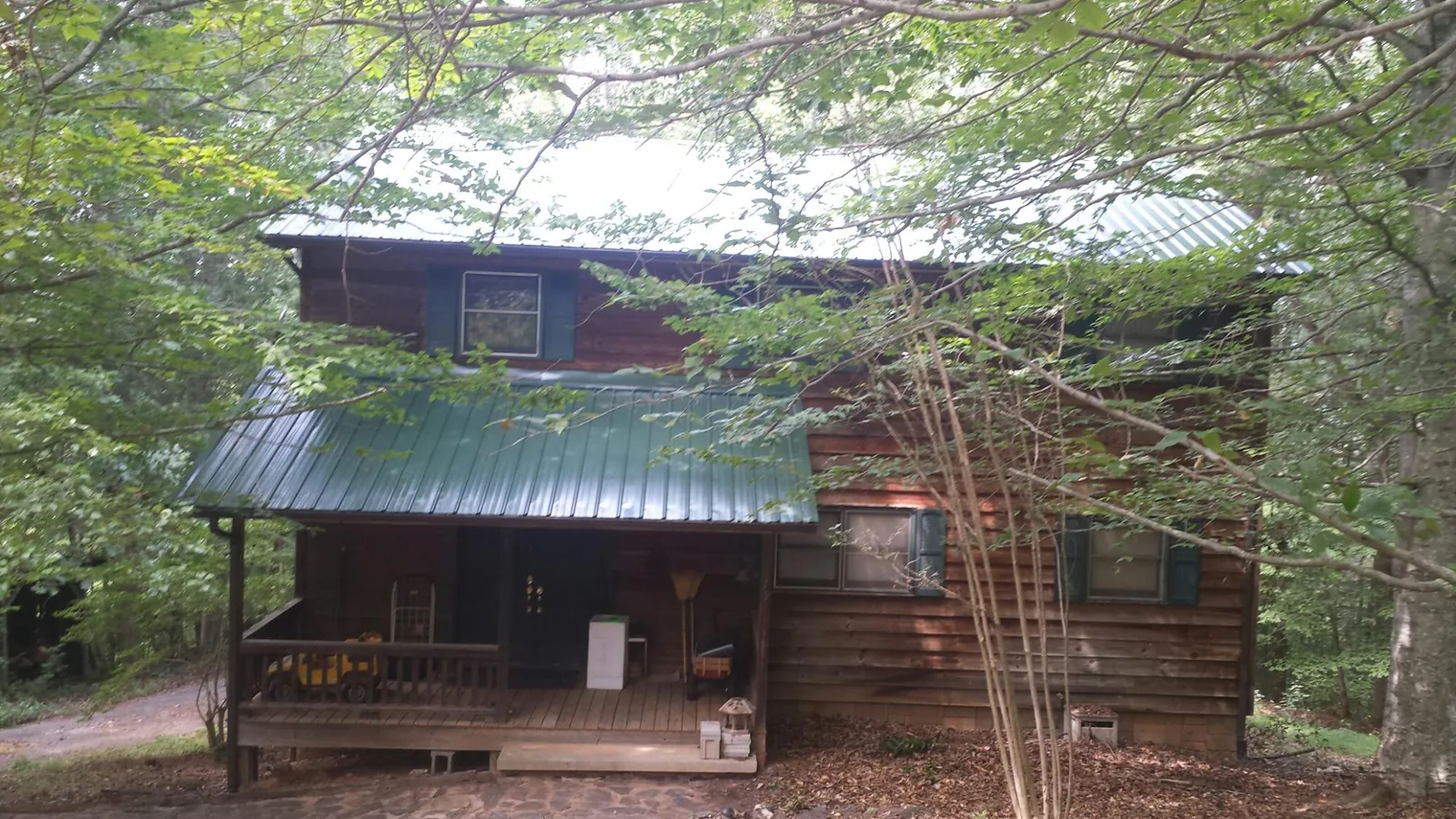 Green metal roof and covered porch on a log cabin in Center City