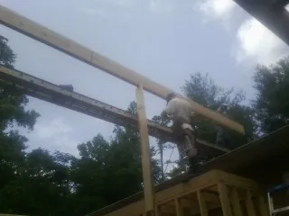 Carpenter setting a ridge beam over a new addition frame — Ice Dam Removal by Roofing Brothers in Center City