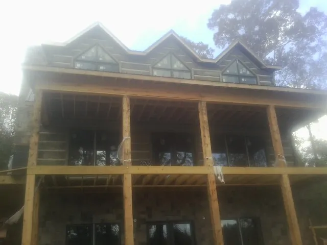 Dormers and porch framing on a large log home under construction — Roof Coating work by our crew in Center City