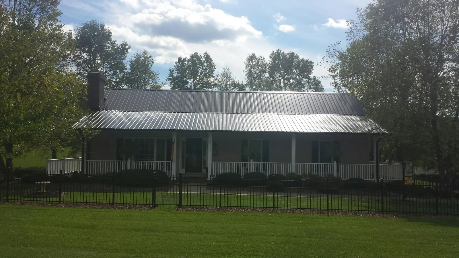 Gray metal roof on a brick ranch with a full width front porch — Gutter Guard Installation work by our crew in Center City