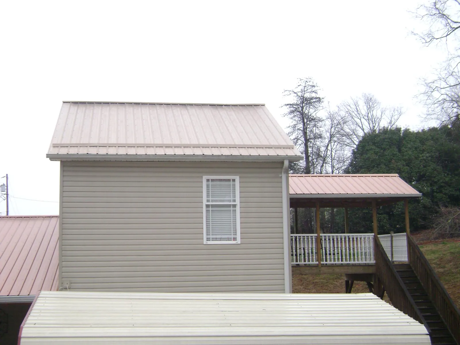 Tan metal roofs on a two story addition and attached porch, from a Roof Replacement job in Center City