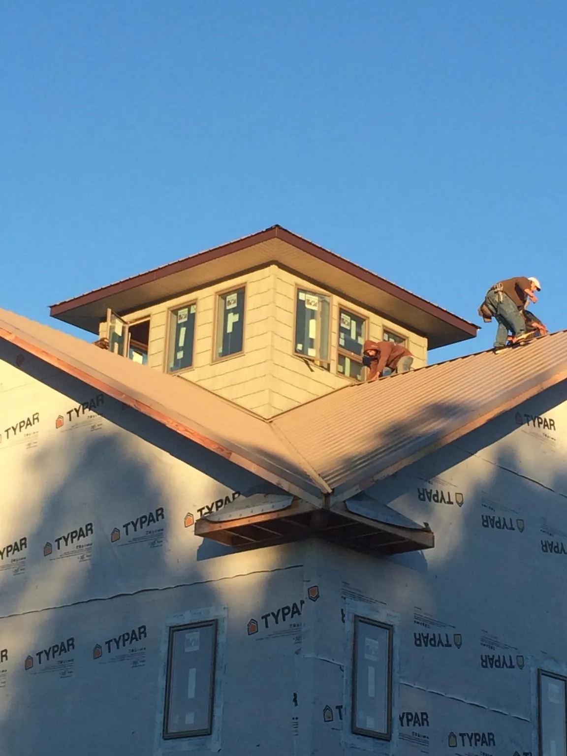 Roofers working around a rooftop cupola on a new metal roof at sunset — Roof Waterproofing in Center City by Roofing Brothers